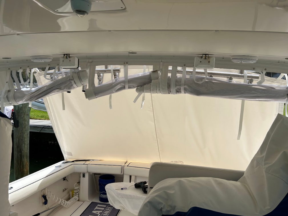 Boat interior with a white canvas shade extended, under a white structure with fishing rod holders.