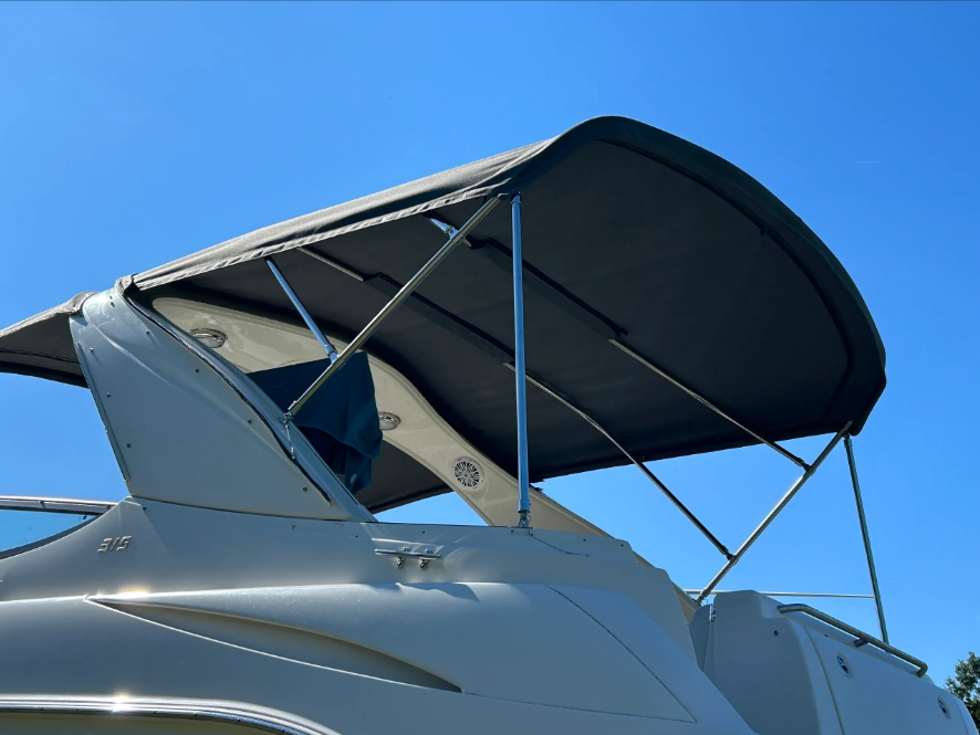 Boat with a dark grey canopy against a clear blue sky.