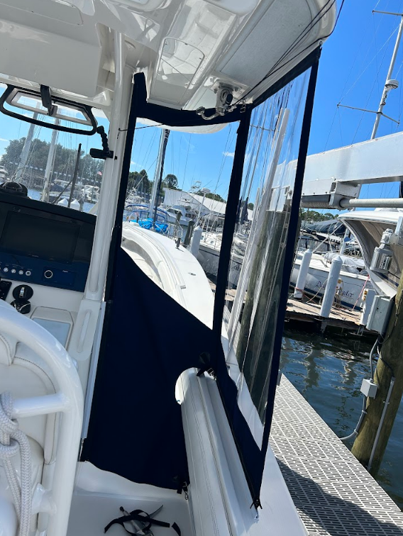 Boat cabin with clear vinyl enclosure. Blue fabric trim. Sunny outdoor setting near a dock.