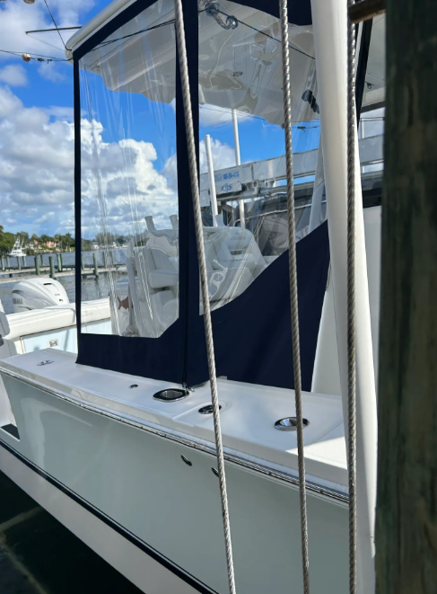 White boat with clear enclosure, blue accents. Water and sky in the background.