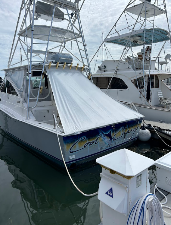 A white boat with a large, white awning is docked. 