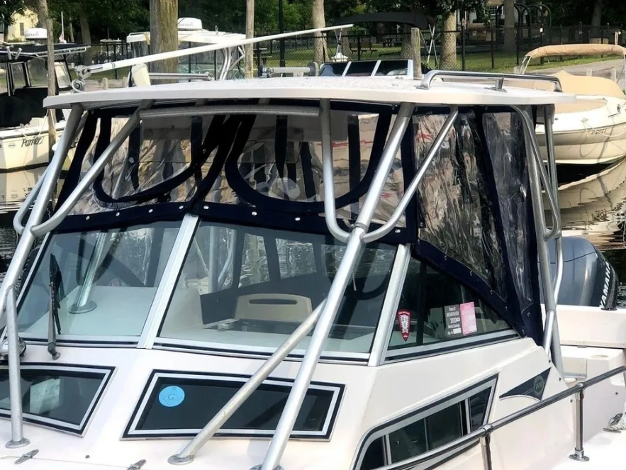 Boat with clear vinyl enclosures, stainless steel frame, docked at a marina.