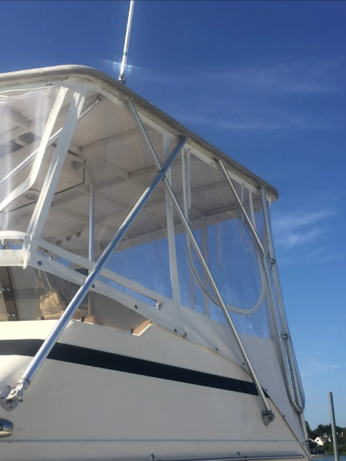 Boat cabin with clear vinyl windows against a blue sky.