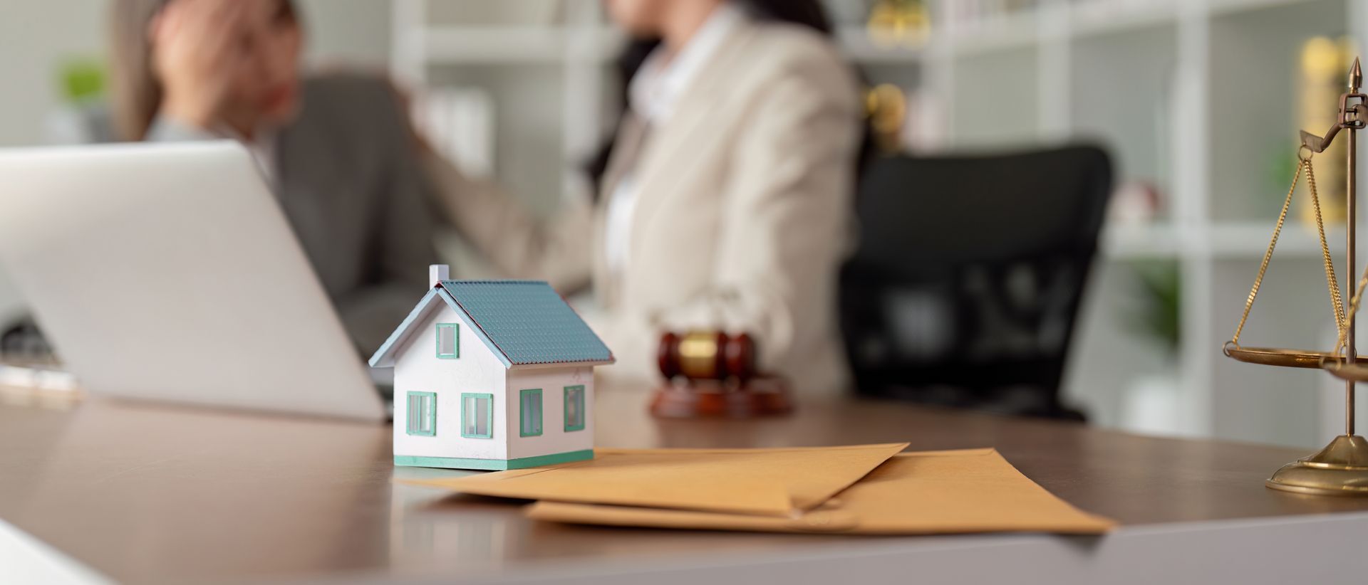 Model house and legal documents on desk during estate planning meeting. Model house and legal documents on desk during estate planning meeting.