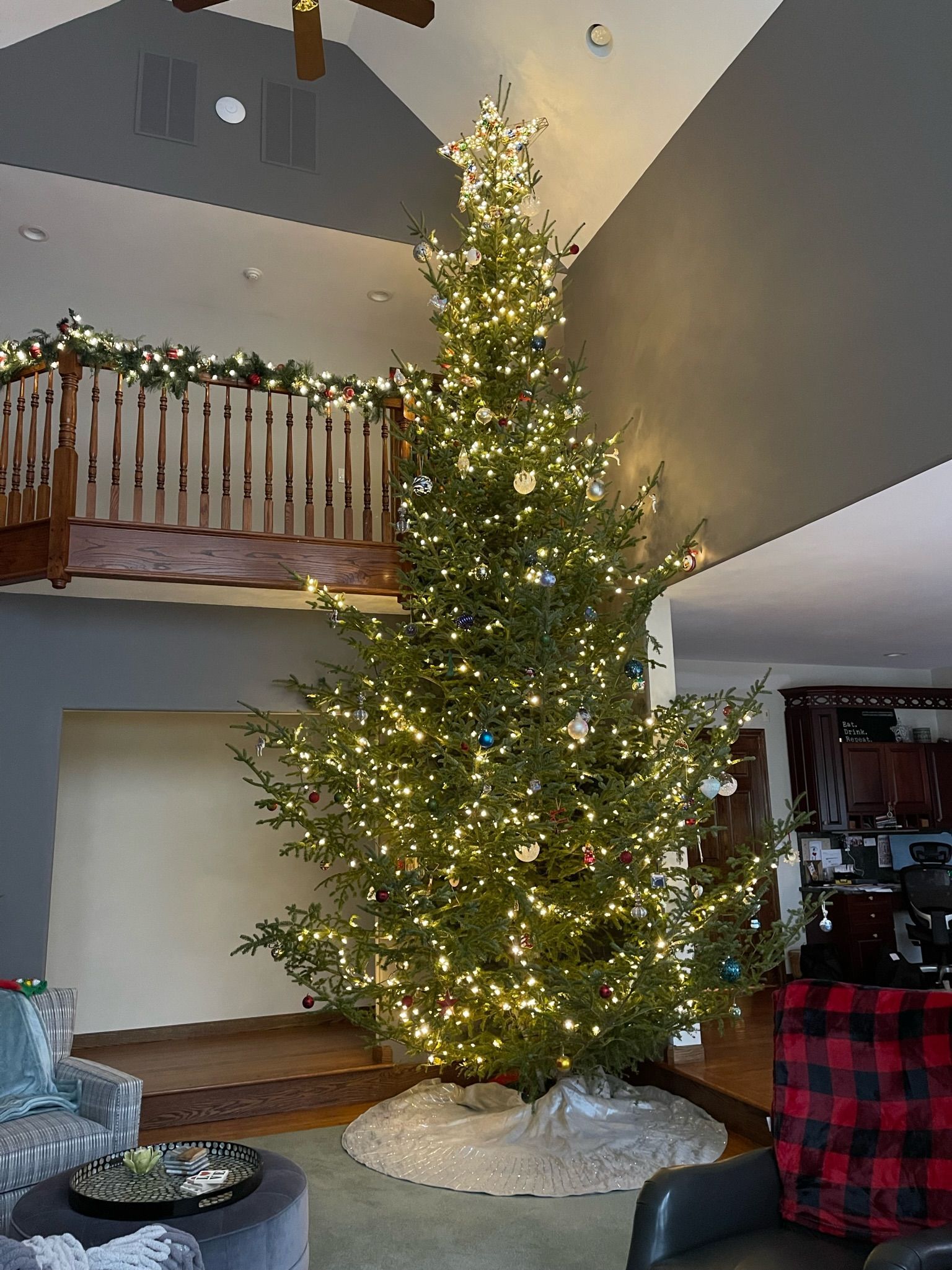 A large christmas tree is in the middle of a living room.