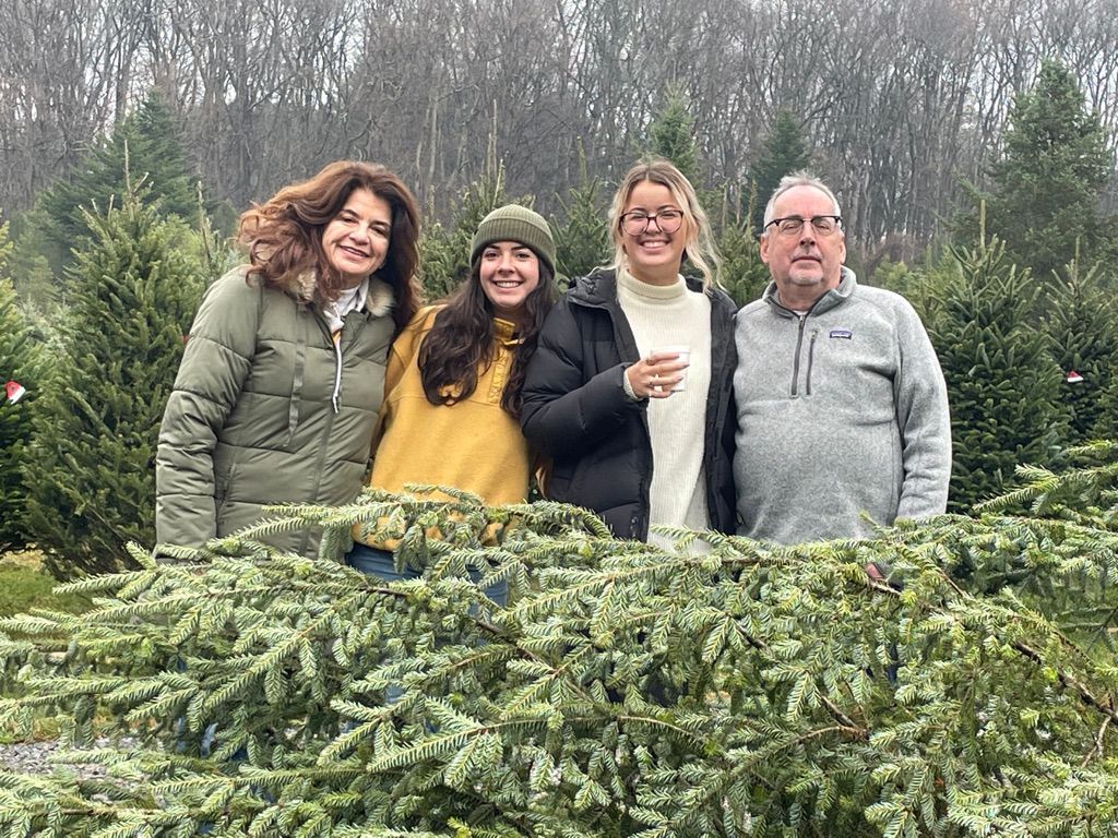 A family is posing for a picture in a field of christmas trees.
