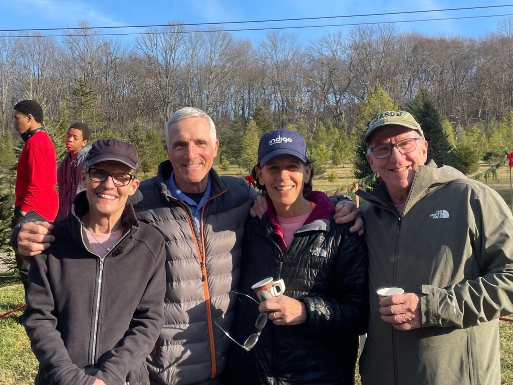 A group of people are posing for a picture at a christmas tree farm.