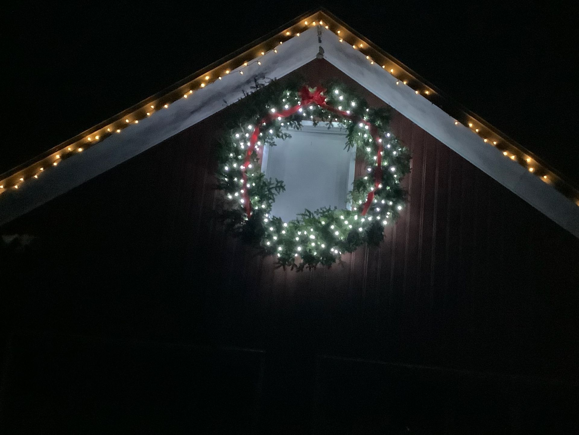 A christmas wreath is lit up on the side of a building