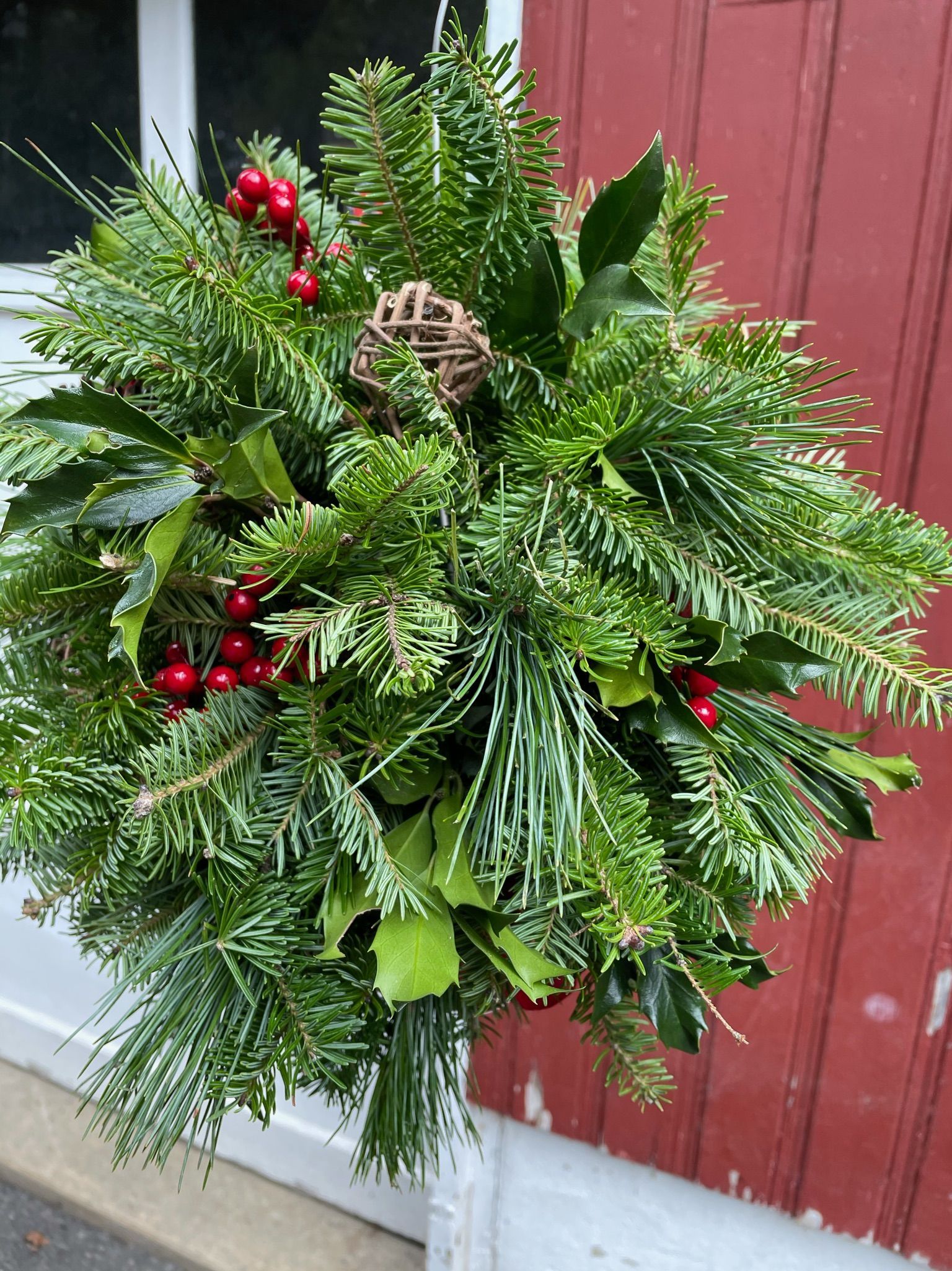 A christmas wreath is sitting in front of a red building.