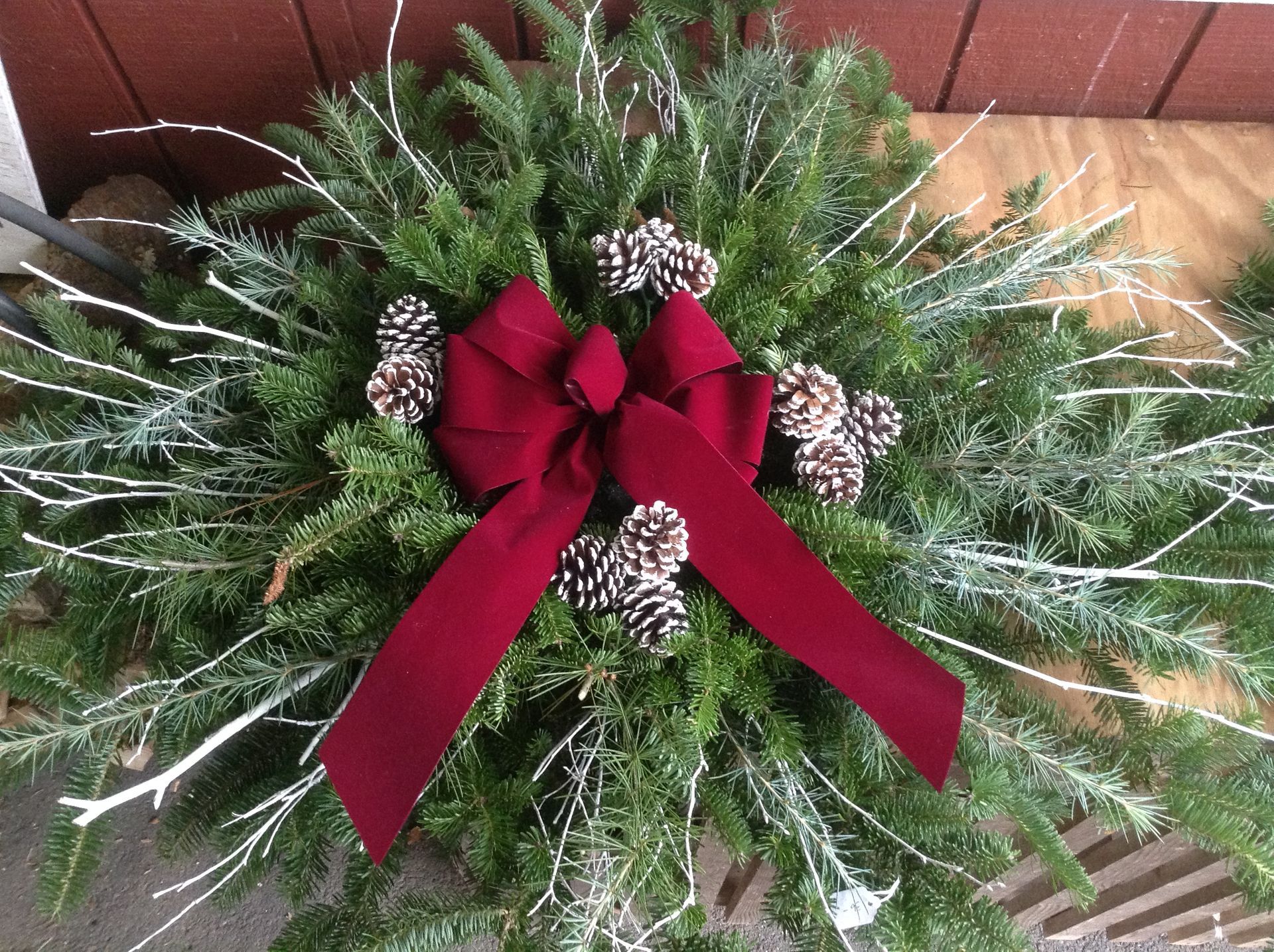 A christmas wreath with pine cones and a red bow