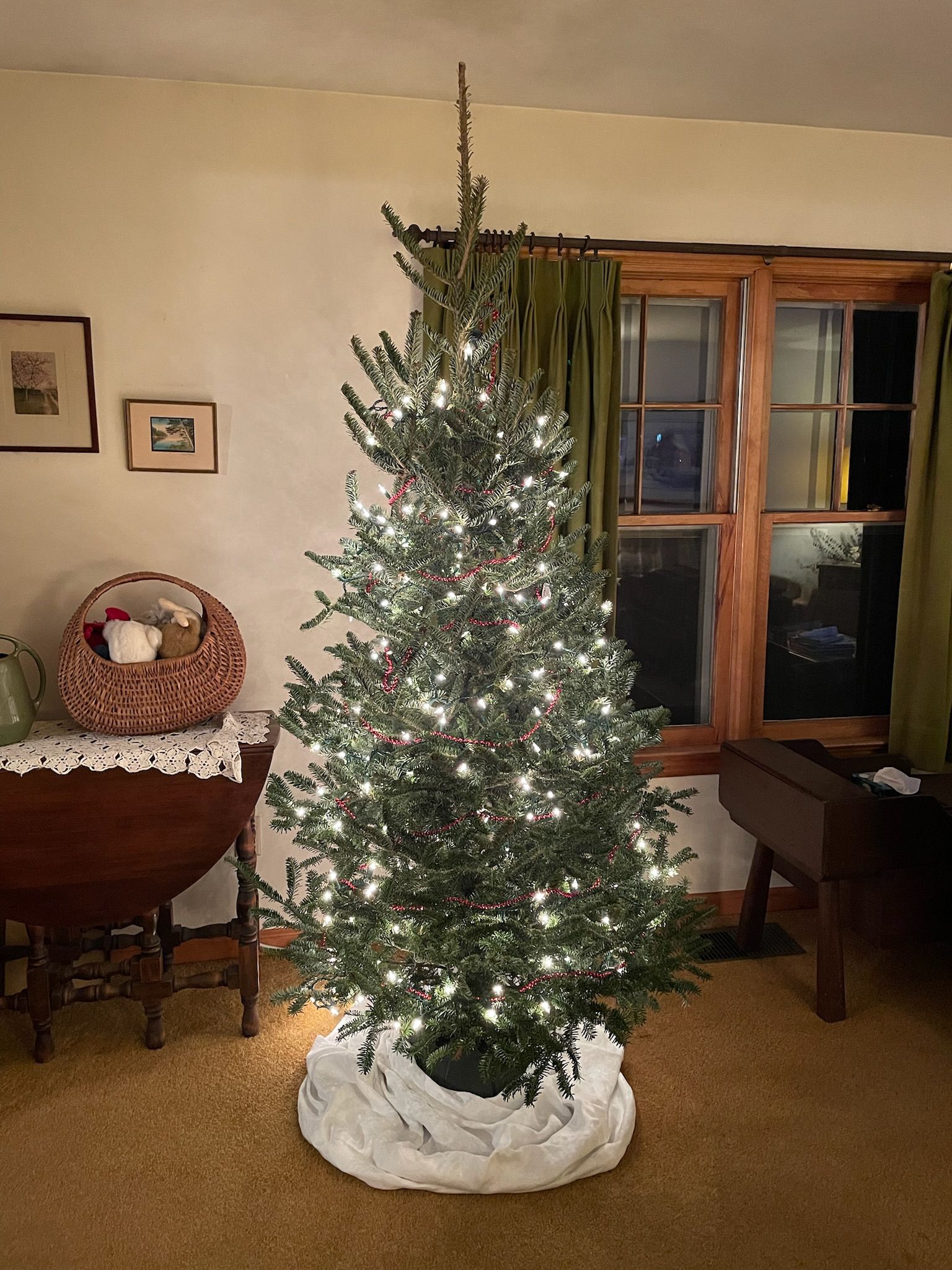 A christmas tree is sitting in a living room next to a window.