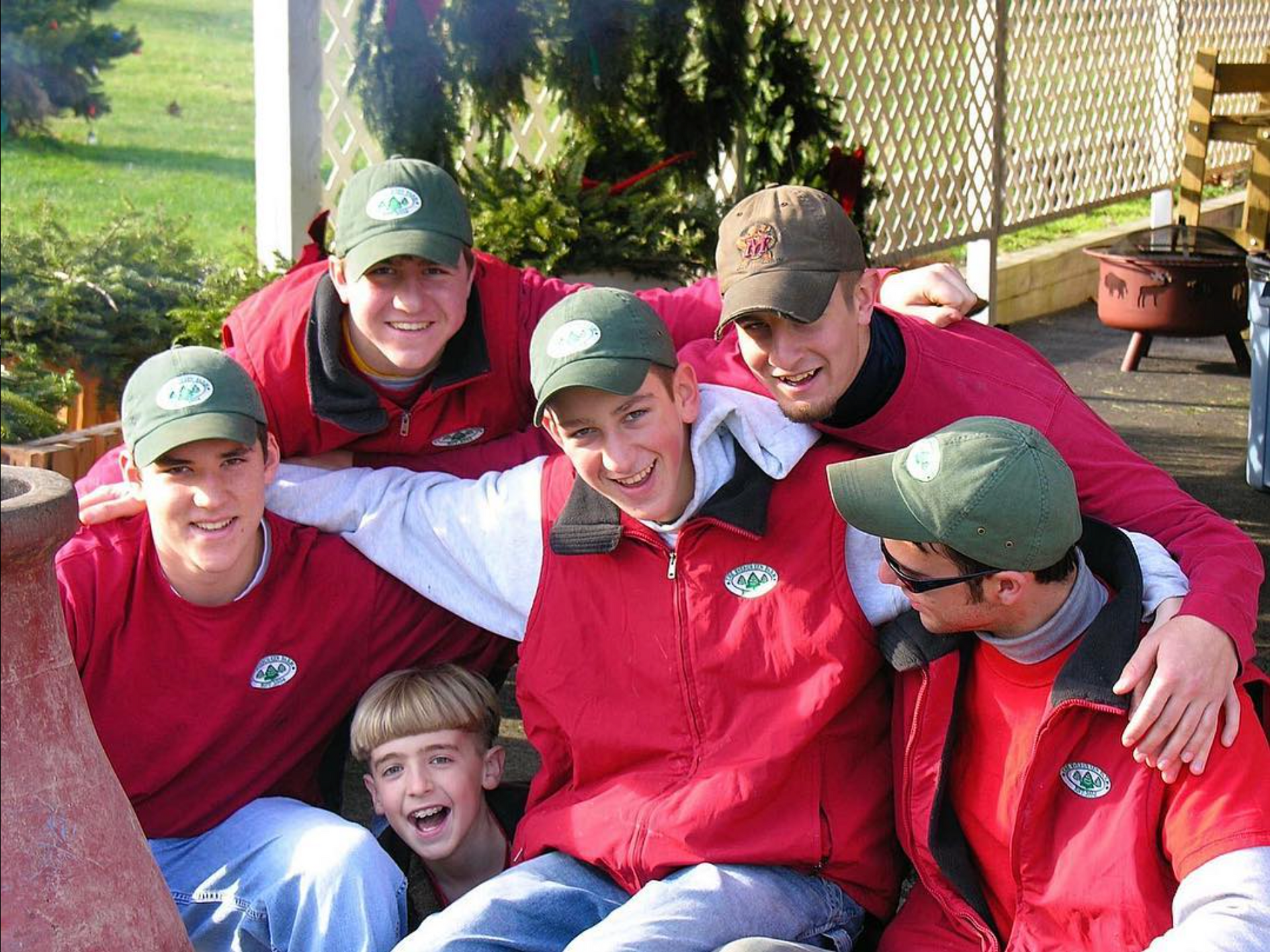 A group of people wearing red jackets and green hats are posing for a picture
