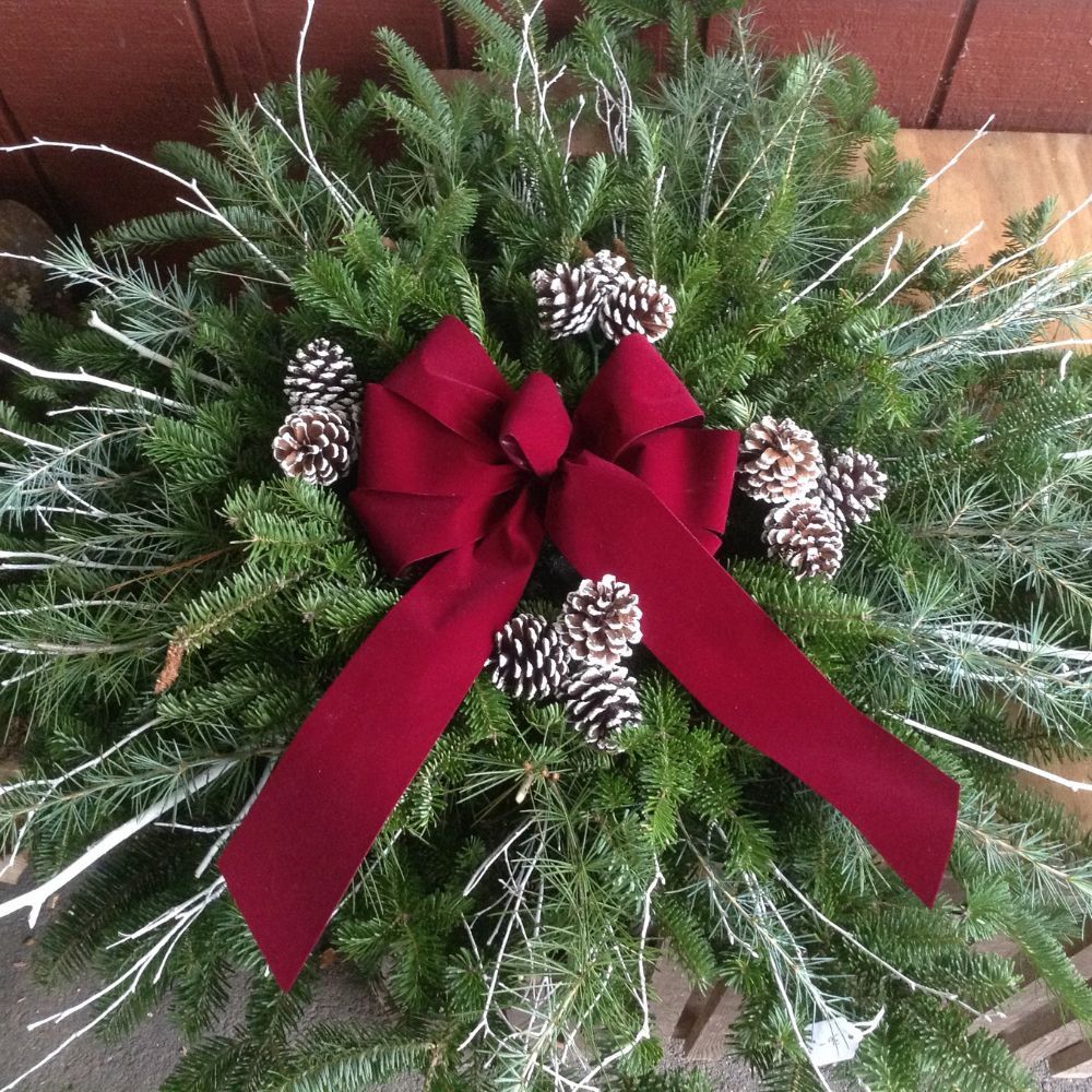 A christmas wreath with pine cones and a red bow