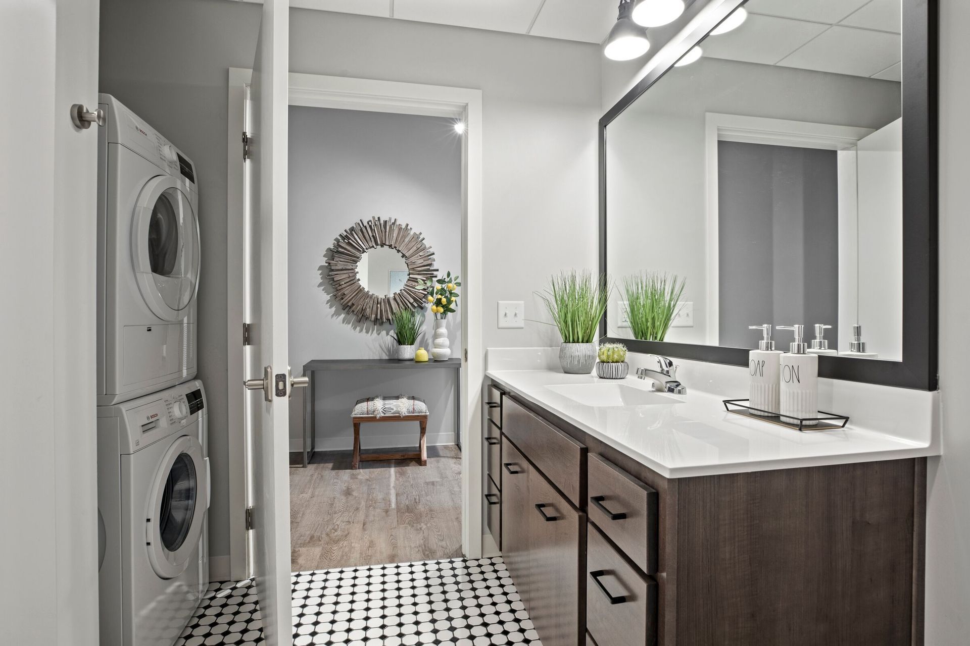 Bathroom vanity with double sink, large mirror, and a laundry closet with stacked washer/dryer at The Jax in St. Paul, MN.
