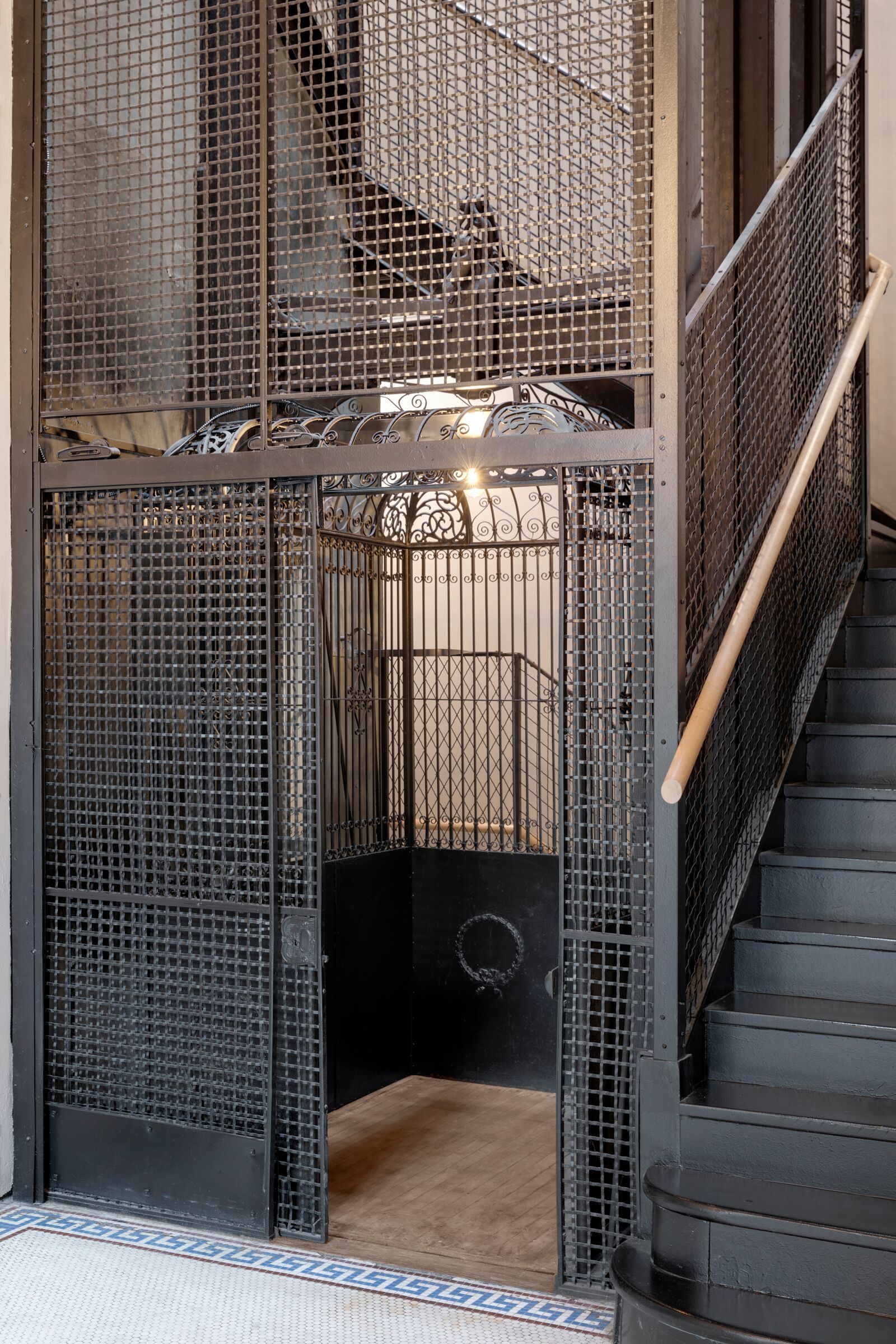 Industrial metal cage elevator and staircase with ornate ironwork inside a multifamily building at The Jax in St. Paul, MN.