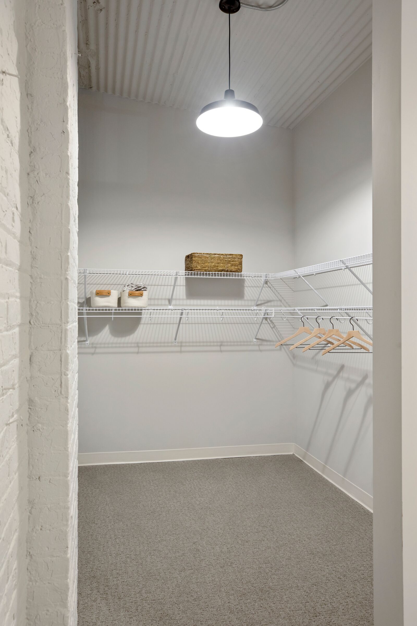 Walk-in closet with white wire shelves, a hanging rod, and a ceiling light at The Jax in St. Paul, MN.