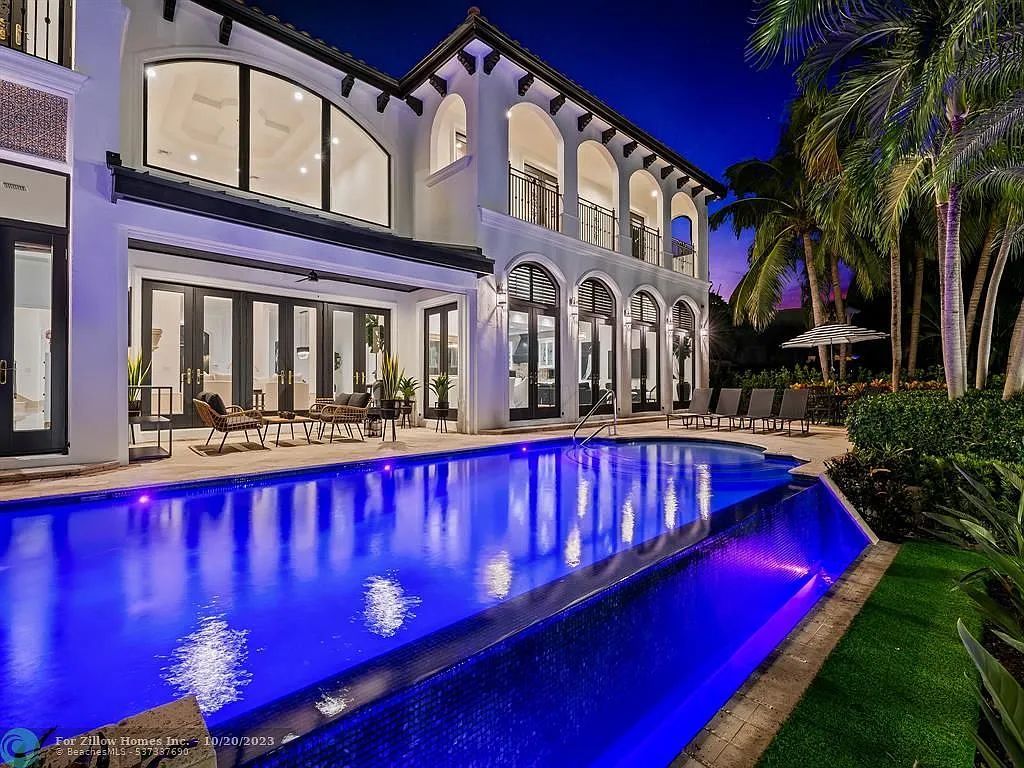 A large white house with a large swimming pool in front of it.