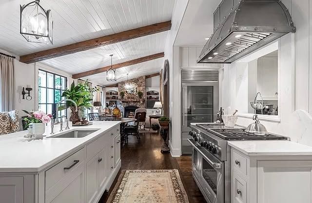 A kitchen with white cabinets , stainless steel appliances , a stove and a sink.