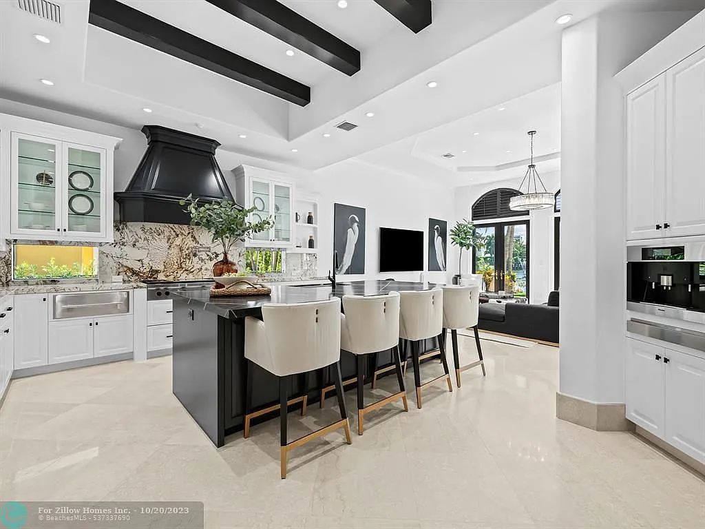 A kitchen with white cabinets , a black island , and stools.