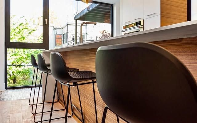 A kitchen with a bar and stools and a large window.
