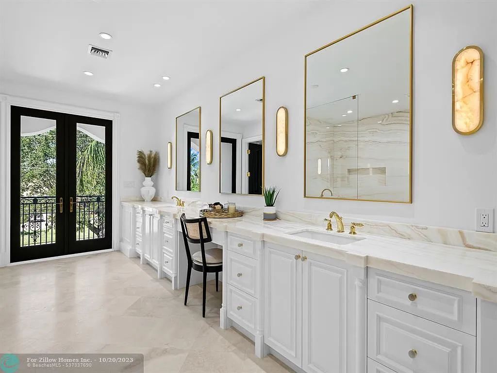 A bathroom with white cabinets , sinks and mirrors.