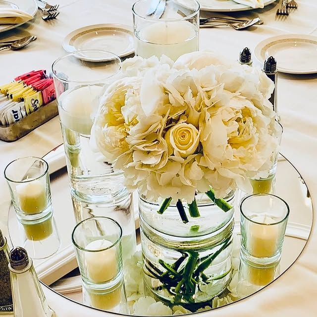 A table with a vase of flowers and candles on it