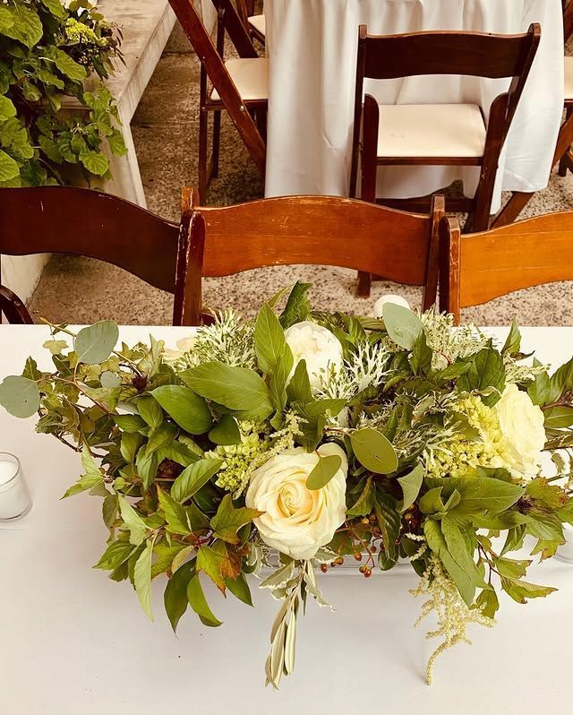 A table with a vase of flowers and leaves on it.