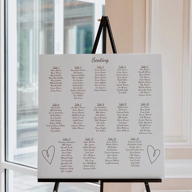 A seating chart is on an easel in front of a window