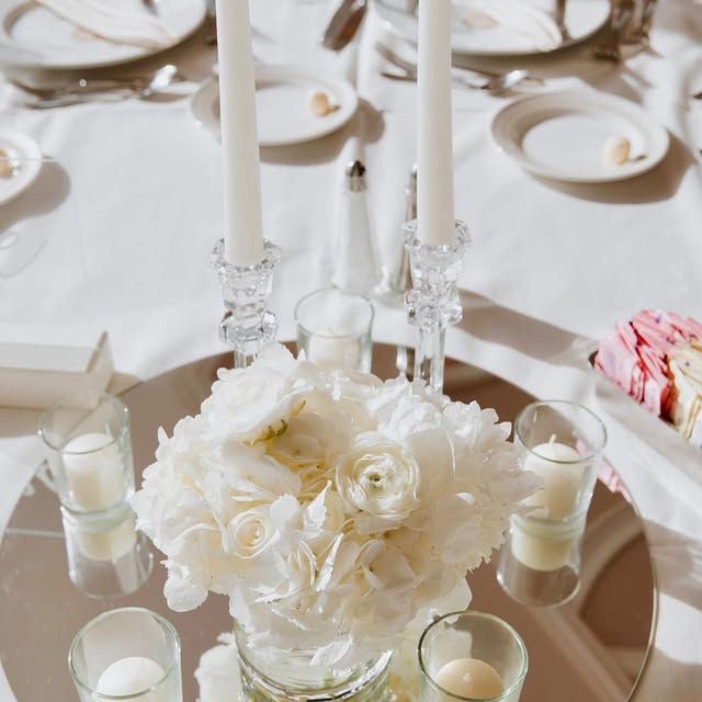 A table with a vase of flowers and candles on it