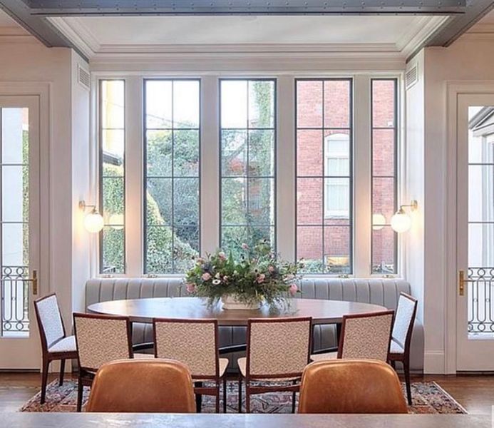A dining room with a table and chairs and a vase of flowers