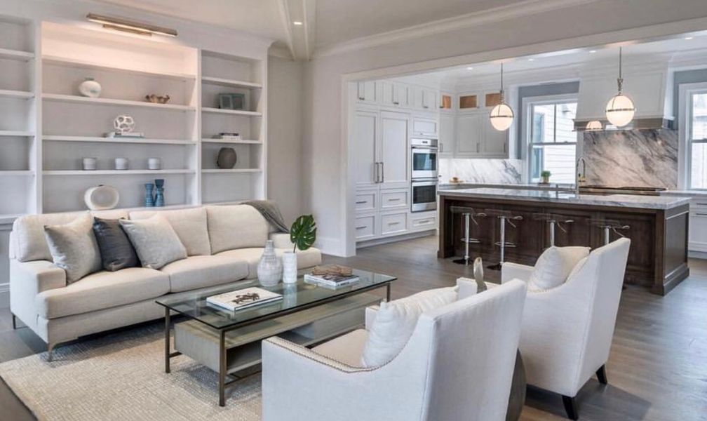 A living room with a couch, chairs, coffee table and shelves