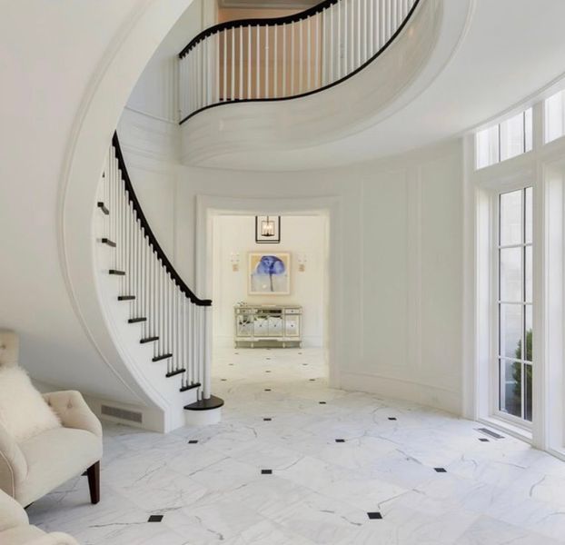 A curved staircase in a hallway with a chair