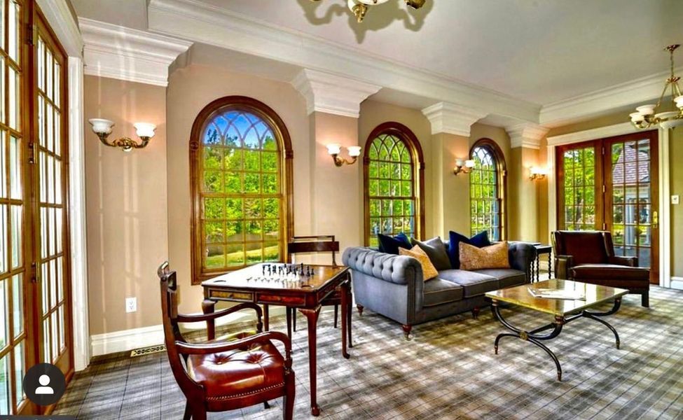 A living room with a couch, table, chairs and windows