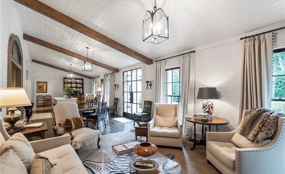 A living room with a couch, chairs, lamps and a table