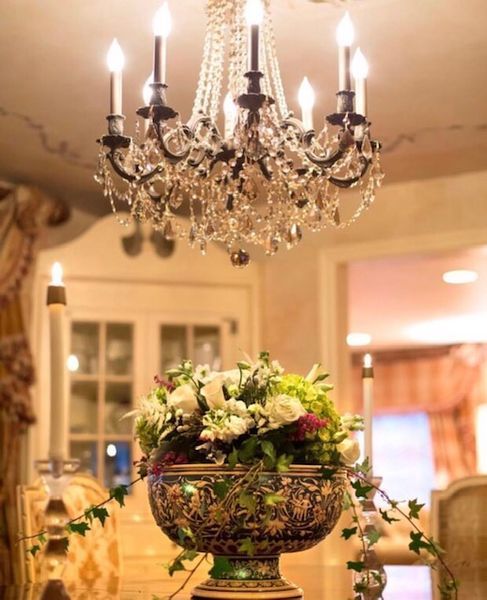 A vase of flowers sits under a chandelier in a dining room