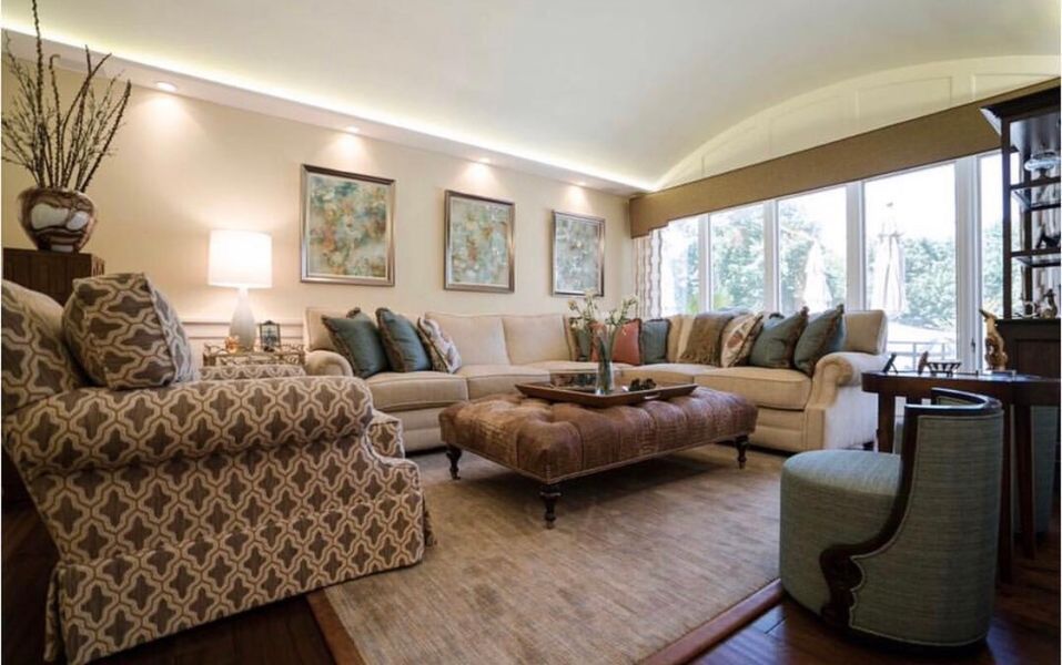 A living room with a large sectional couch, two chairs, a coffee table and a rug