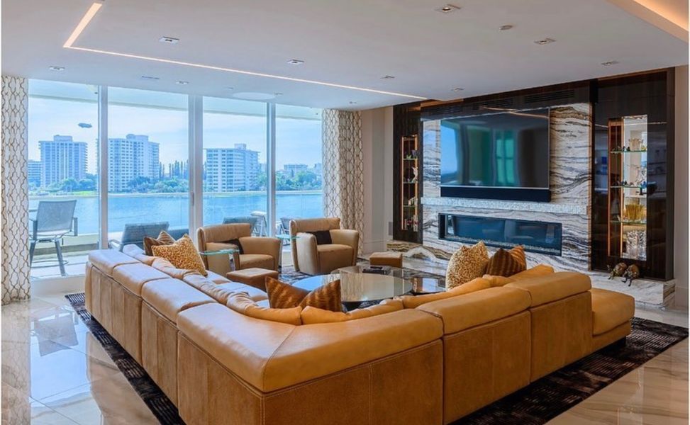 A living room with a large sectional couch, chairs, a fireplace and a flat screen tv