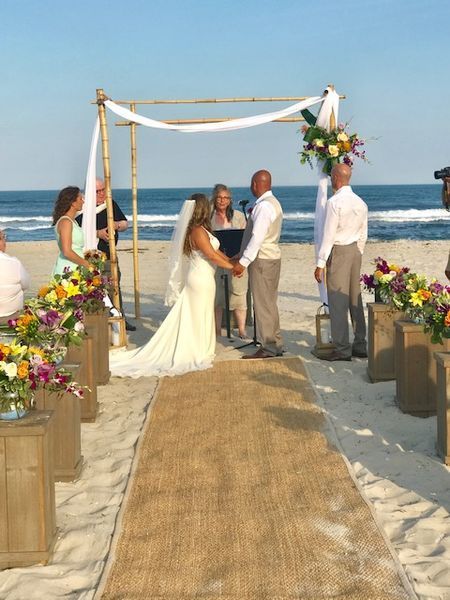 A bride and groom are holding hands during their wedding ceremony on the beach