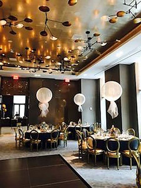 A large room with tables and chairs and balloons hanging from the ceiling