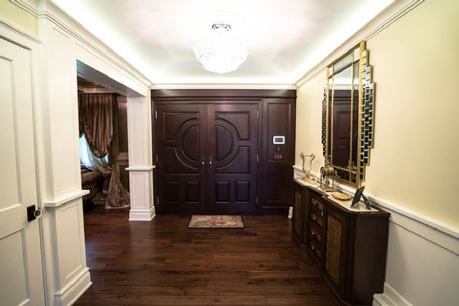 A hallway with hardwood floors, a mirror and a chandelier
