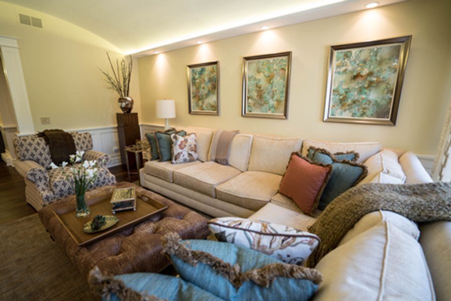 A living room with a couch, chairs, coffee table and paintings on the wall