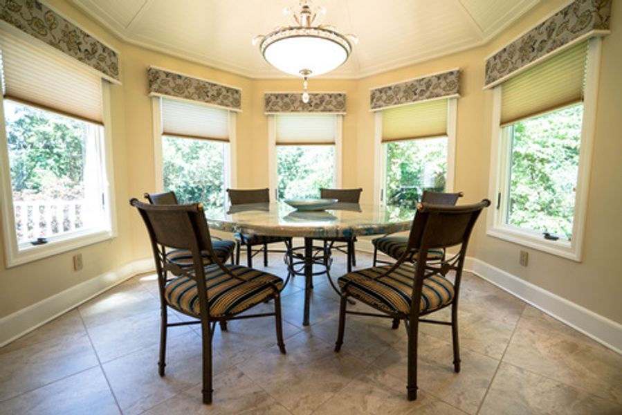 A dining room with a table and chairs and lots of windows