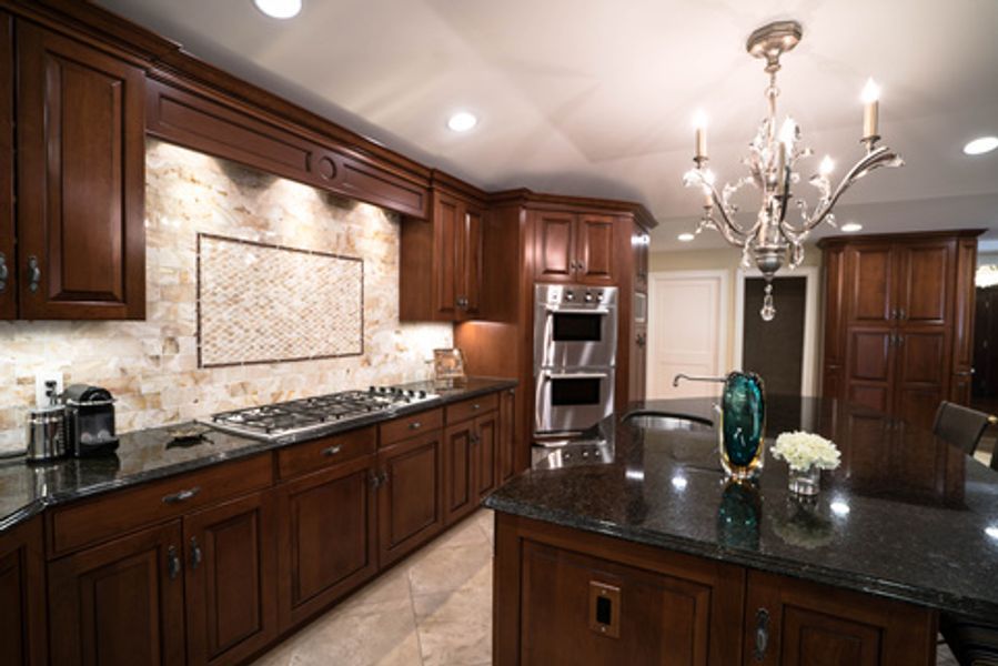 A kitchen with wooden cabinets, granite counter tops, stainless steel appliances and a large island