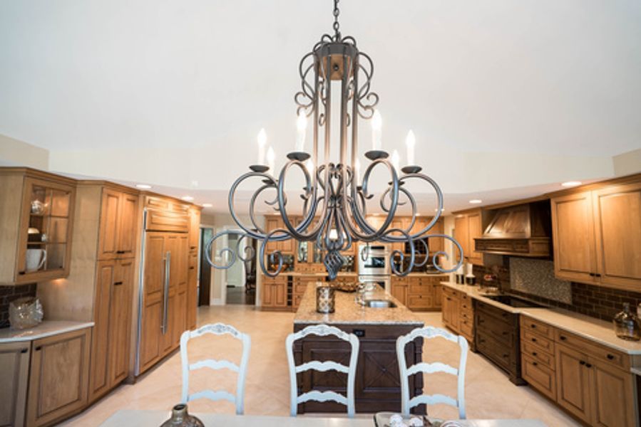A kitchen with wooden cabinets and a large chandelier hanging from the ceiling