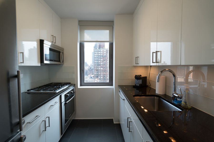 A kitchen with white cabinets and black counter tops