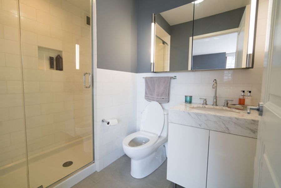 A bathroom with a toilet, sink, shower and mirror