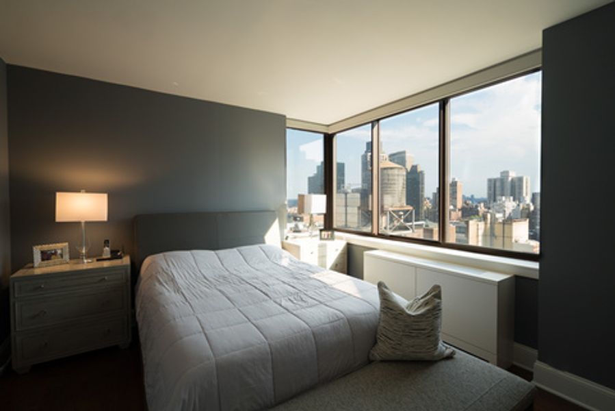 A bedroom with a large bed and a view of the city