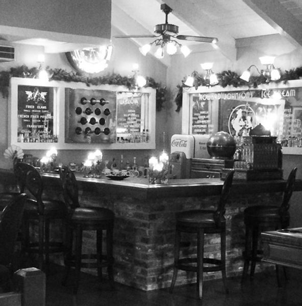 A black and white photo of a bar with a coca cola machine