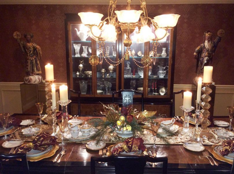 A dining room table with plates candles and a chandelier