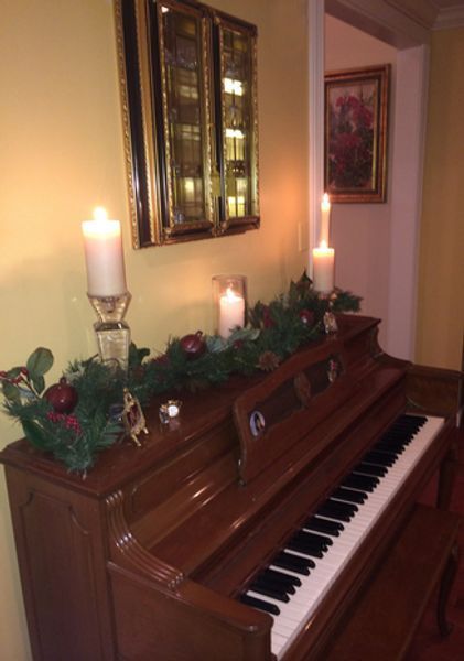A piano is decorated with candles and christmas decorations